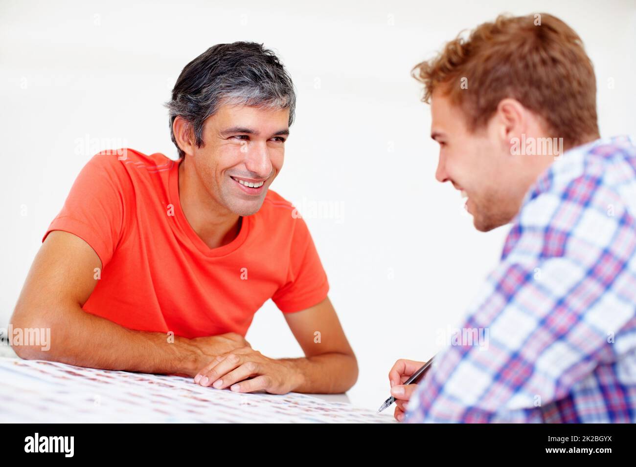 Photographes souriants en discussion. Deux photographes souriants assis à table pour discuter. Banque D'Images