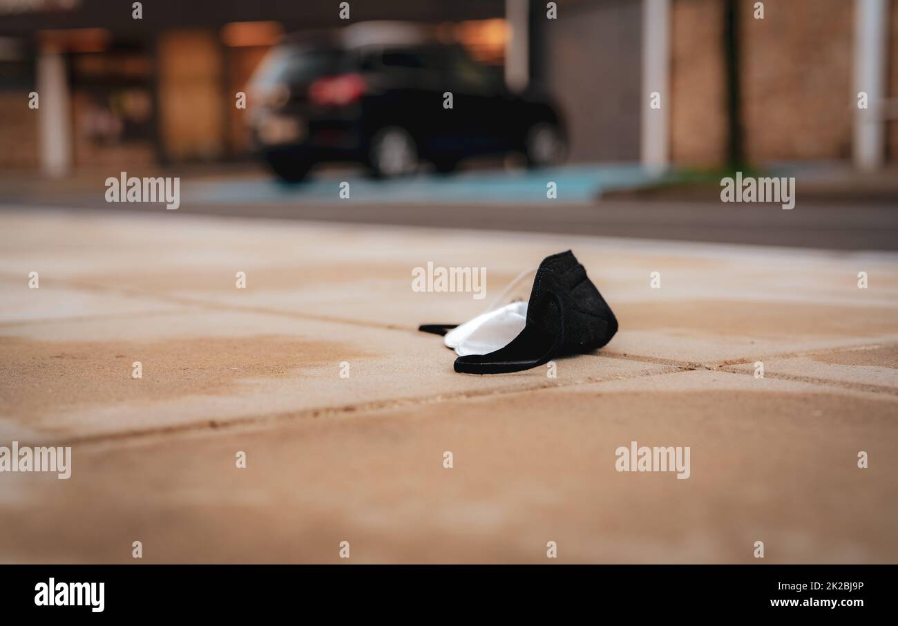 Masque médical utilisé jeter sur le sol sur une voiture floue dans le stationnement et le bâtiment de la ville. Déchets médicaux. Ville sale. Masque médical pour le visage déchets d'ordures sur le sol. Manque de responsabilité sociale. Mauvaise habitude. Banque D'Images