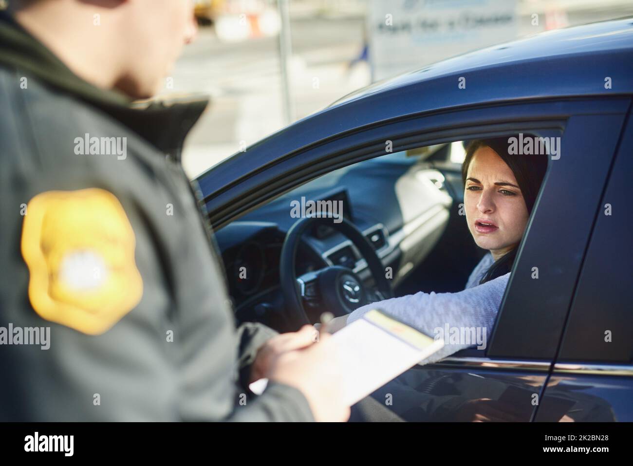 Vous avez dépassé la limite de vitesse. Plan rogné d'un agent de la circulation masculin méconnaissable délivrant un billet à une femme civile à un barrage routier. Banque D'Images