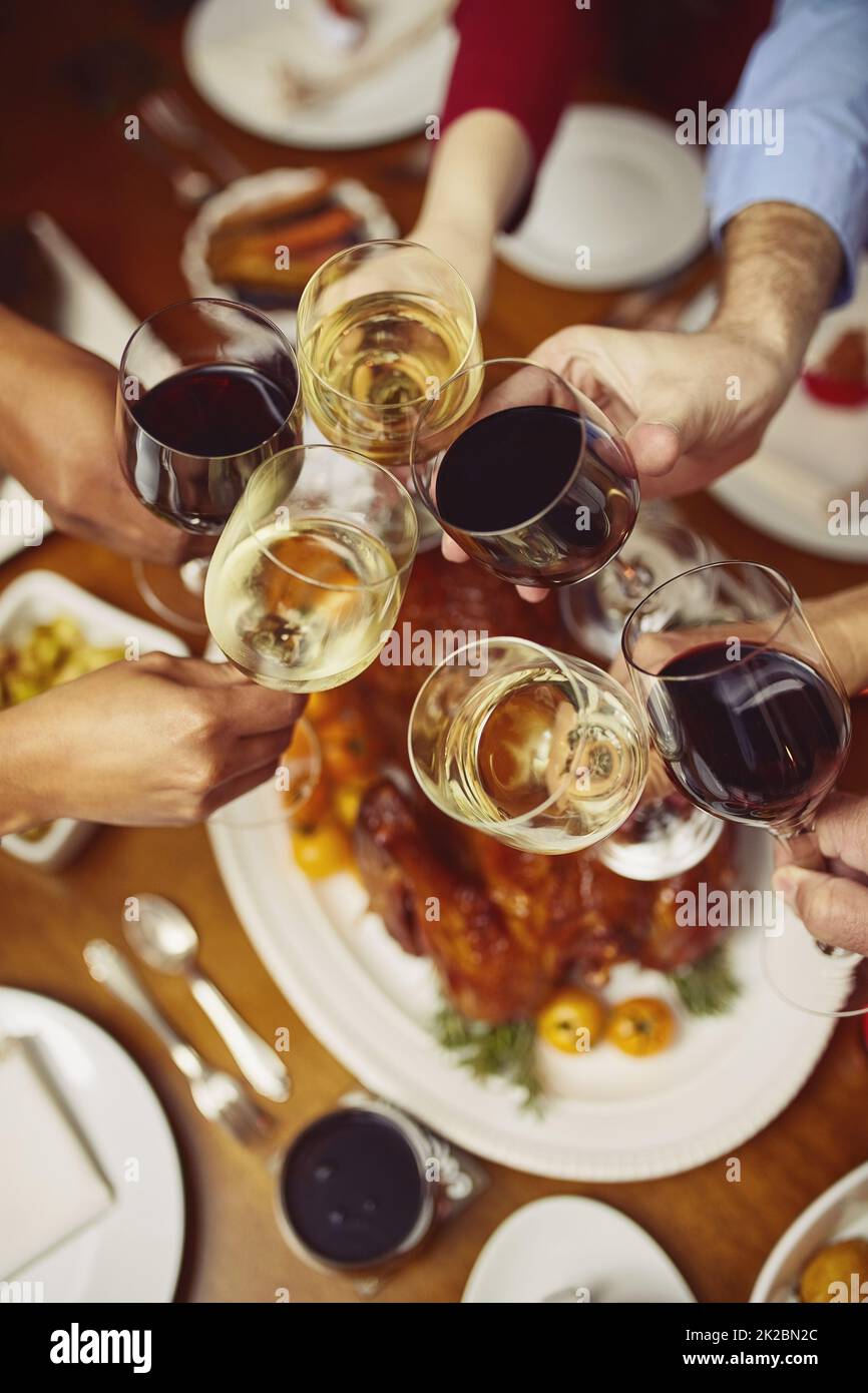 C'est la saison de la joie. Gros plan d'un groupe de personnes qui font un toast à une table de salle à manger. Banque D'Images