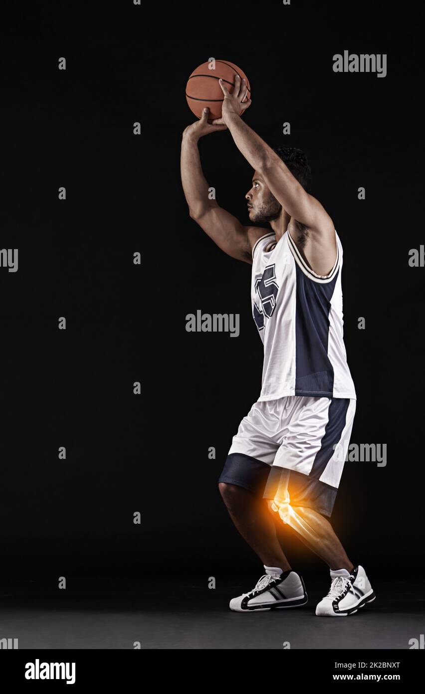Jouez à travers la douleur. Photo en studio d'un jeune joueur de basket-ball avec un genou enflammé. Banque D'Images