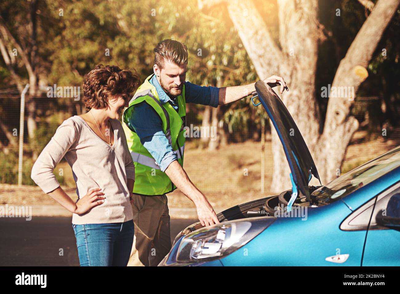 C'est le problème ici. Photo d'une jeune femme qui reçoit l'assistance routière d'un jeune homme après avoir été défait. Banque D'Images