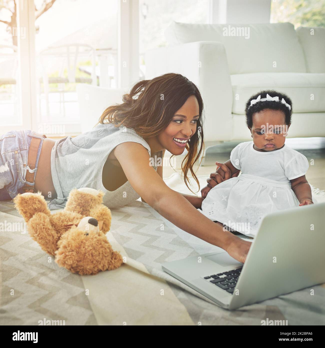 Shes un curieux petit. Prise de vue d'une mère à l'aide d'un ordinateur portable et de sa petite fille à la maison. Banque D'Images
