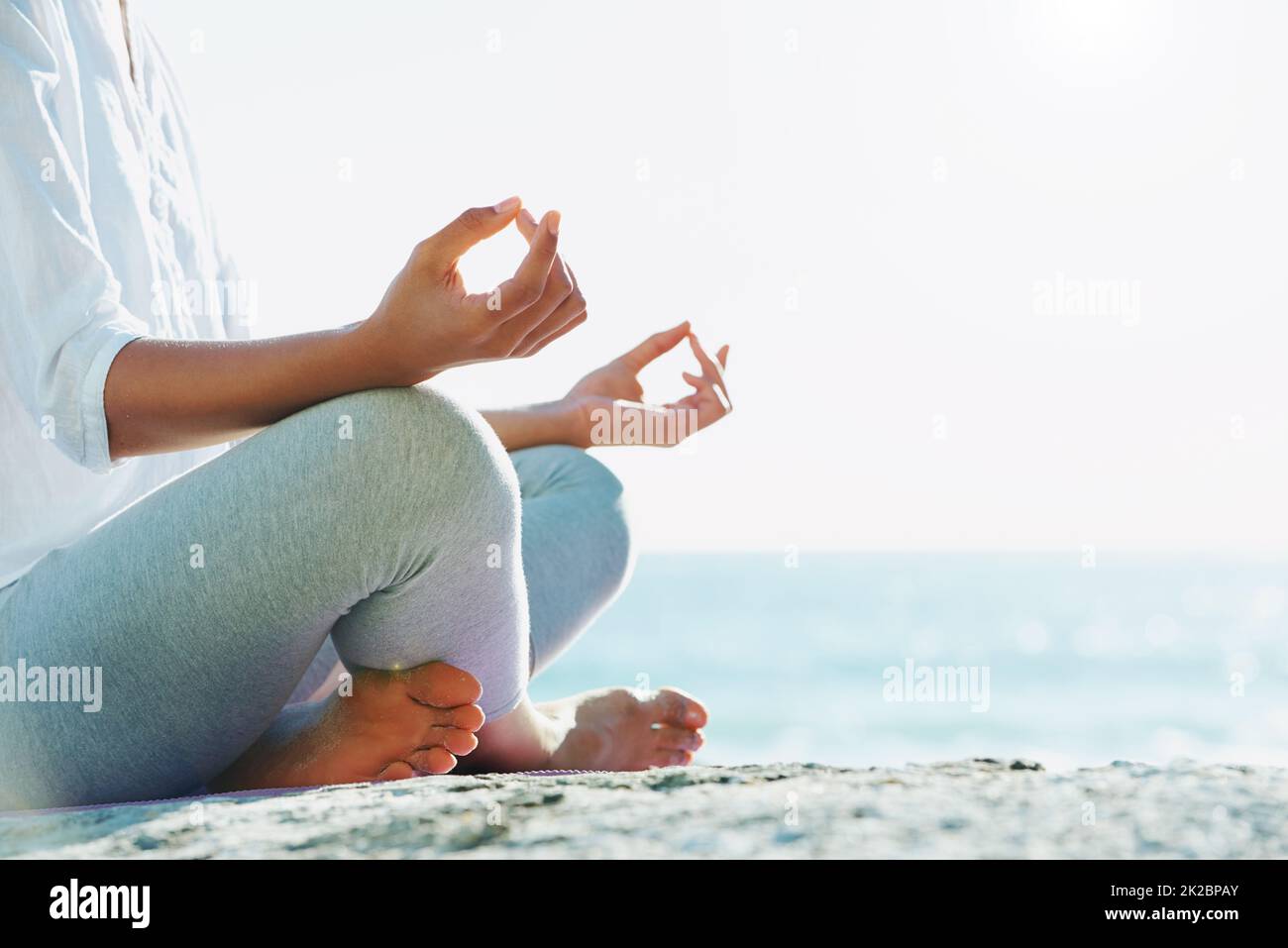 La paix des natures absorbantes. Une jeune femme effectuant une routine de yoga sur la plage sous le soleil d'été. Banque D'Images