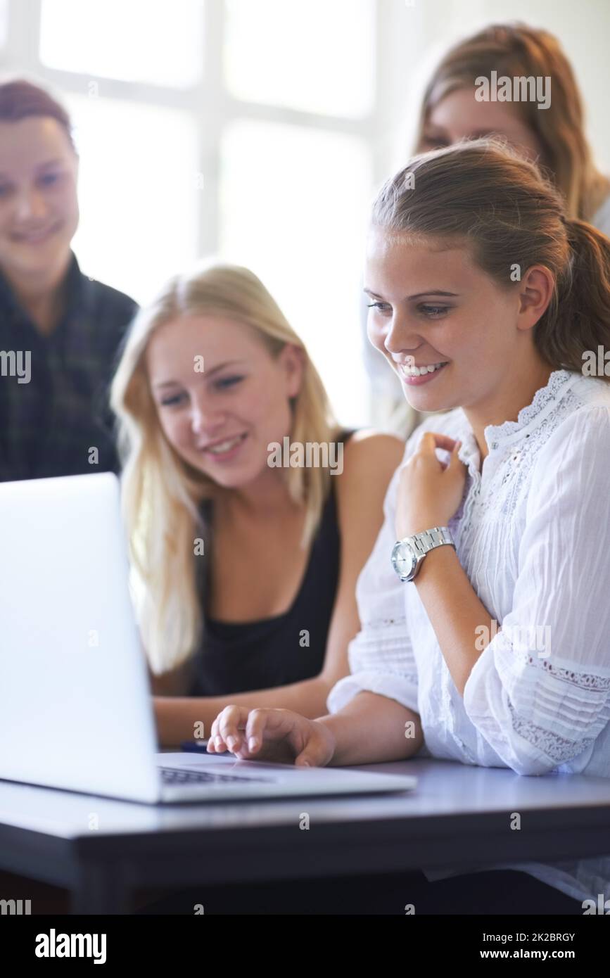 La technologie facilite l'apprentissage. Un groupe d'adolescentes travaillant ensemble sur un ordinateur portable dans la salle de classe. Banque D'Images