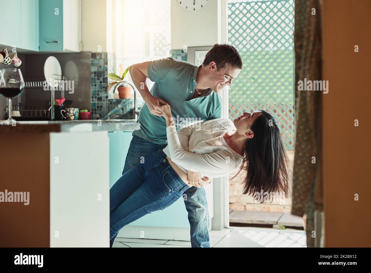 Il me frappe toujours de mes pieds. Photo d'un jeune couple aimant dansant dans la cuisine. Banque D'Images