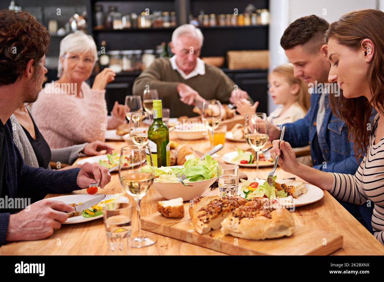 Buvez, mangez et soyez joyeux. Coupe courte d'une famille partageant un repas autour de la table du dîner. Banque D'Images