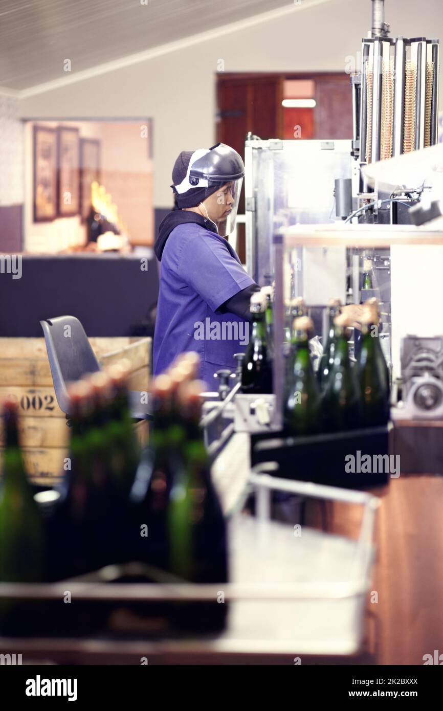 Travailler à l'usine d'embouteillage. Cliché d'un travailleur dans une usine d'embouteillage de vin. Banque D'Images