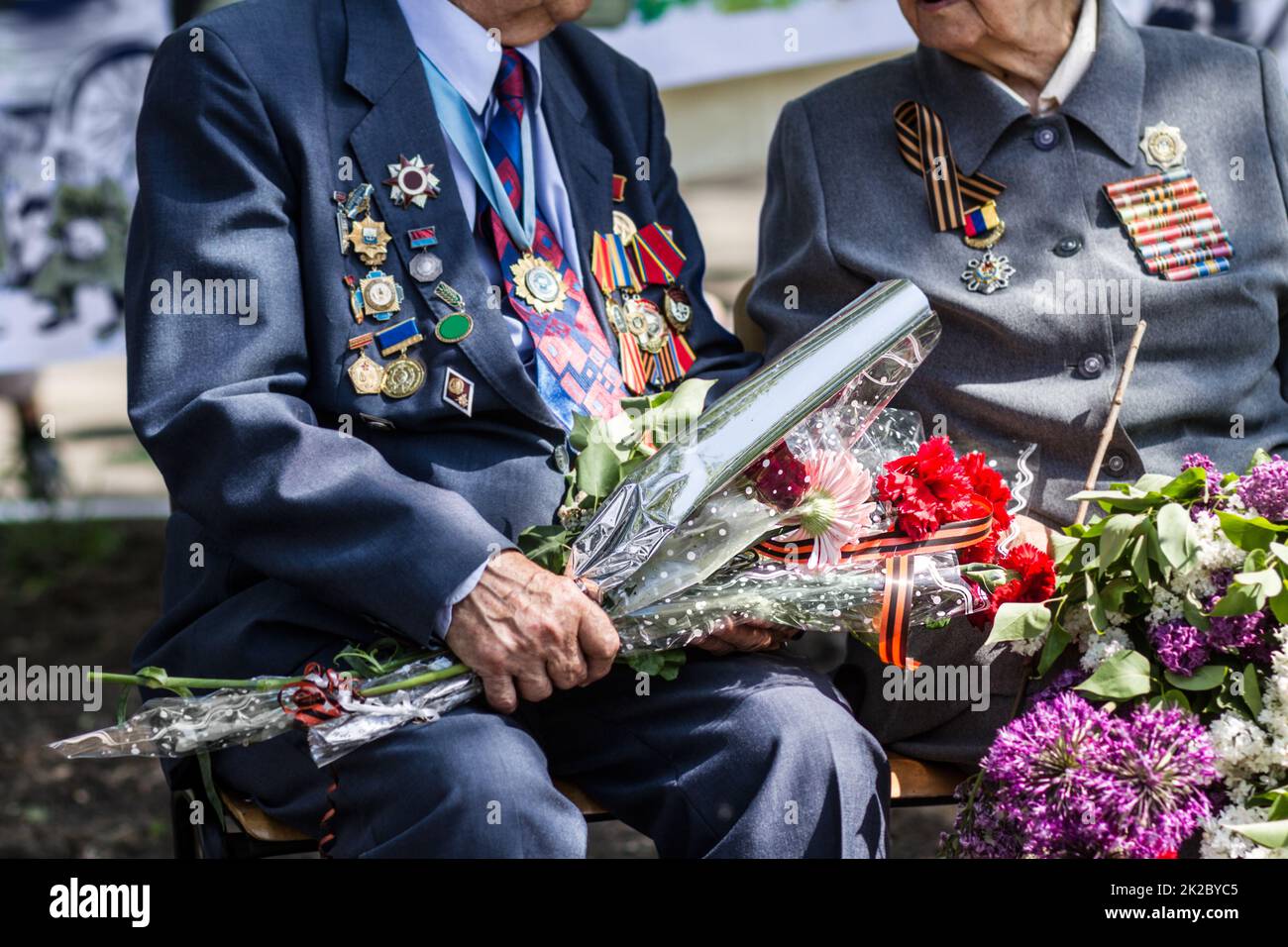 Dire Au revoir à un ami cher. Image rognée de deux anciens combattants de guerre tenant des fleurs à un enterrement. Banque D'Images