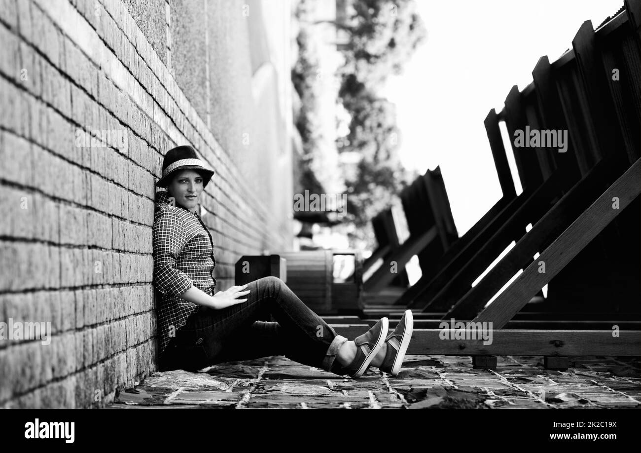 Retourner l'endroit. Une femme semble être assise sur le côté d'un bâtiment avec son dos contre le trottoir - perspective. Banque D'Images