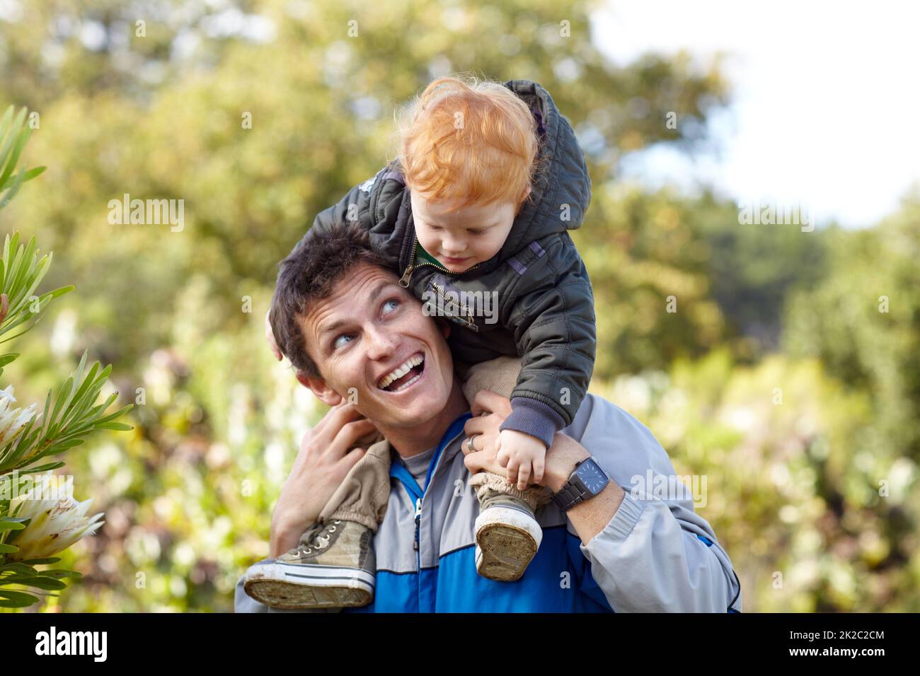 Il aime la nature comme son père. Un jeune père portant son jeune fils sur ses épaules. Banque D'Images