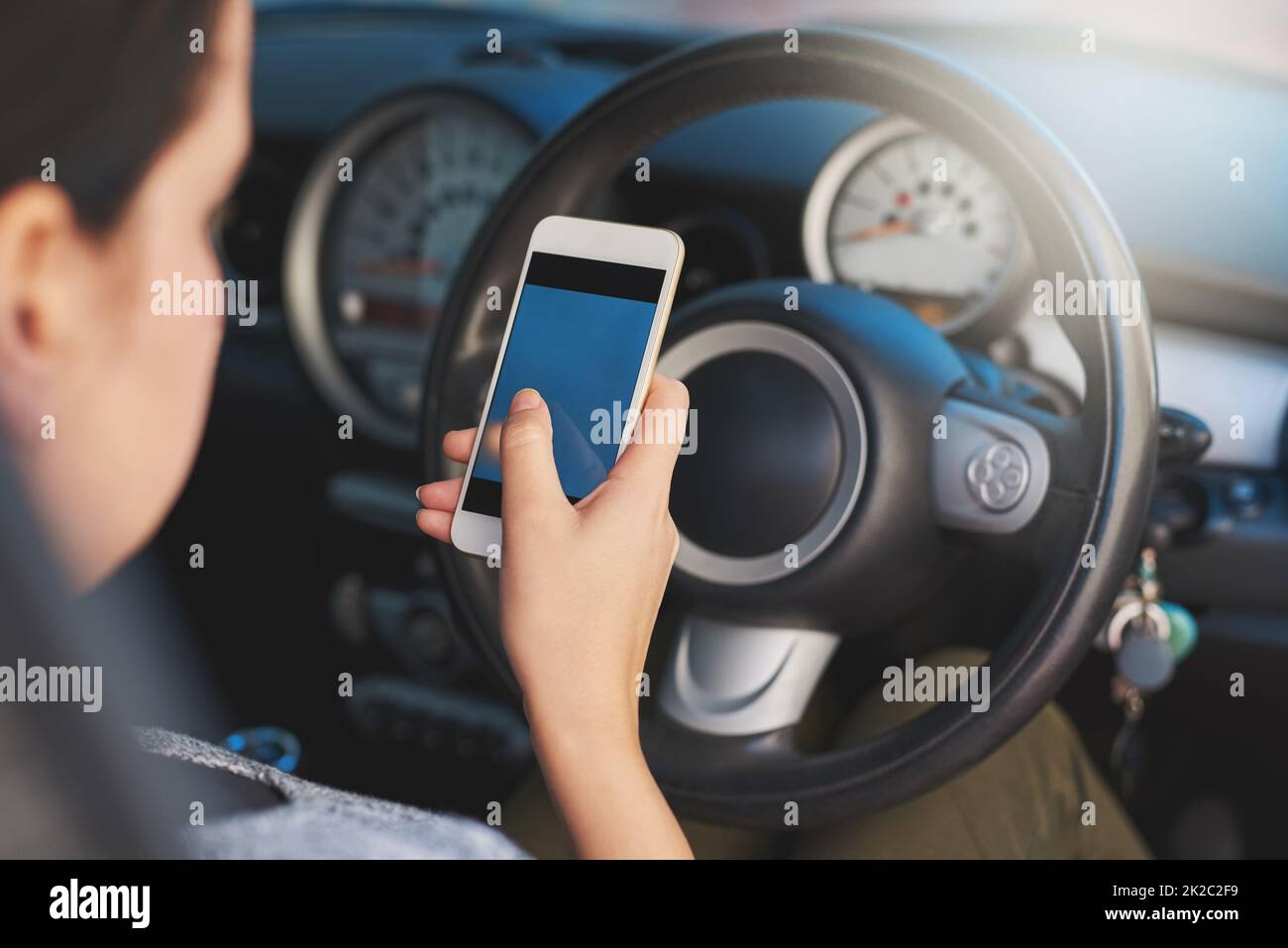 Conduite distraite. Prise de vue d'une femme utilisant un téléphone en conduisant. Banque D'Images