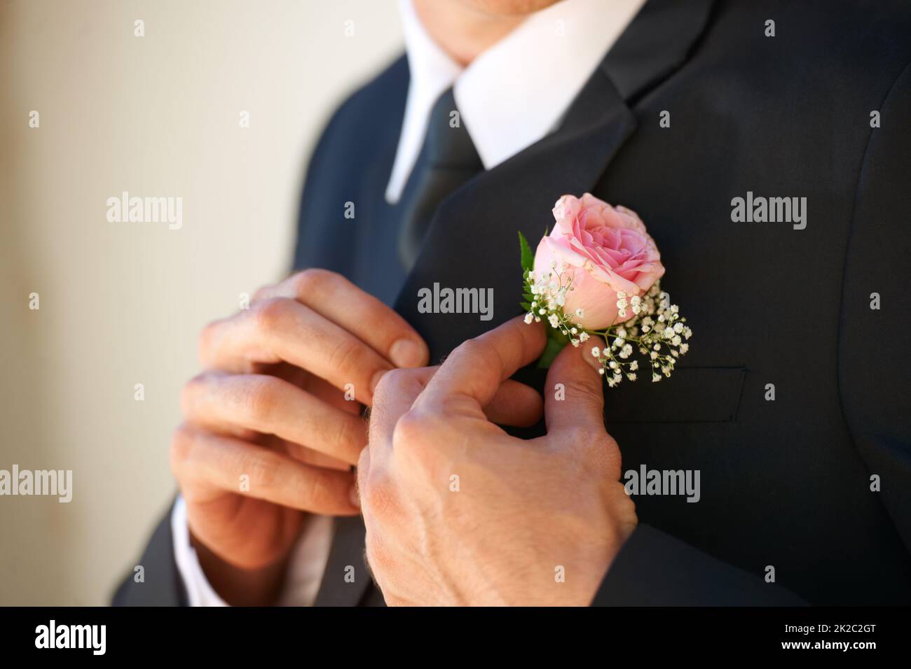 S'assurer qu'il a l'air parfait pour sa femme à être. Image rognée d'un marié en train d'ajuster sa boutonnière avant la cérémonie de mariage. Banque D'Images