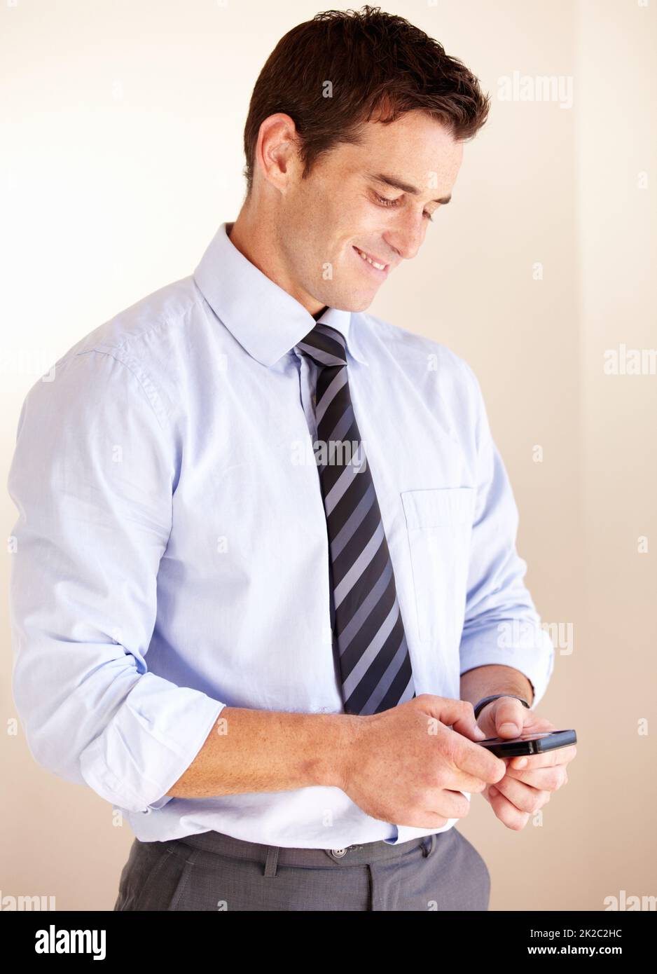 Envoyer un SMS à un être cher. Un jeune homme d'affaires souriant envoie un message texte. Banque D'Images