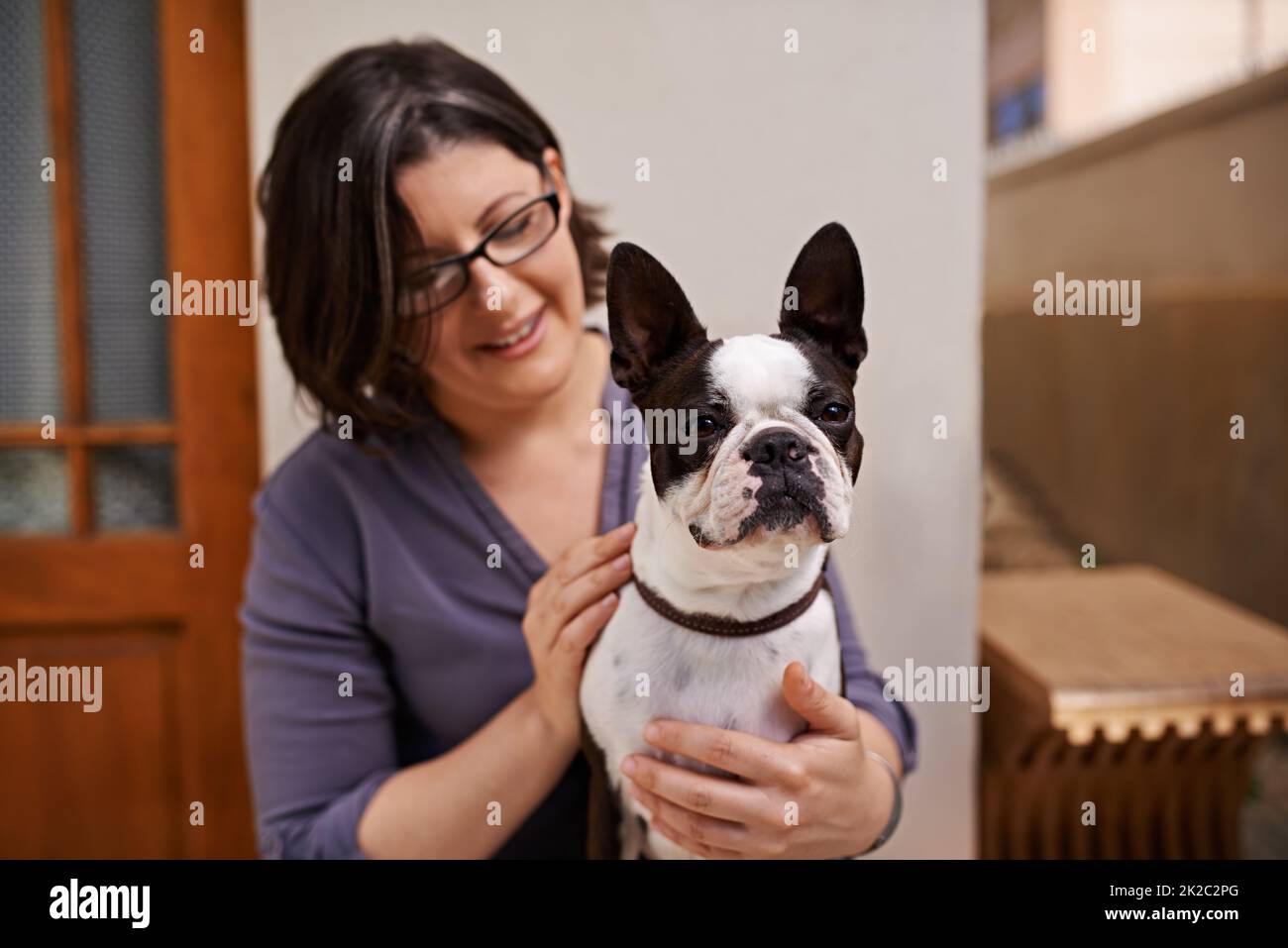 Elle a besoin de beaucoup d'attention. Une femme d'âge moyen assise sur un banc à l'extérieur de sa maison avec son chien. Banque D'Images