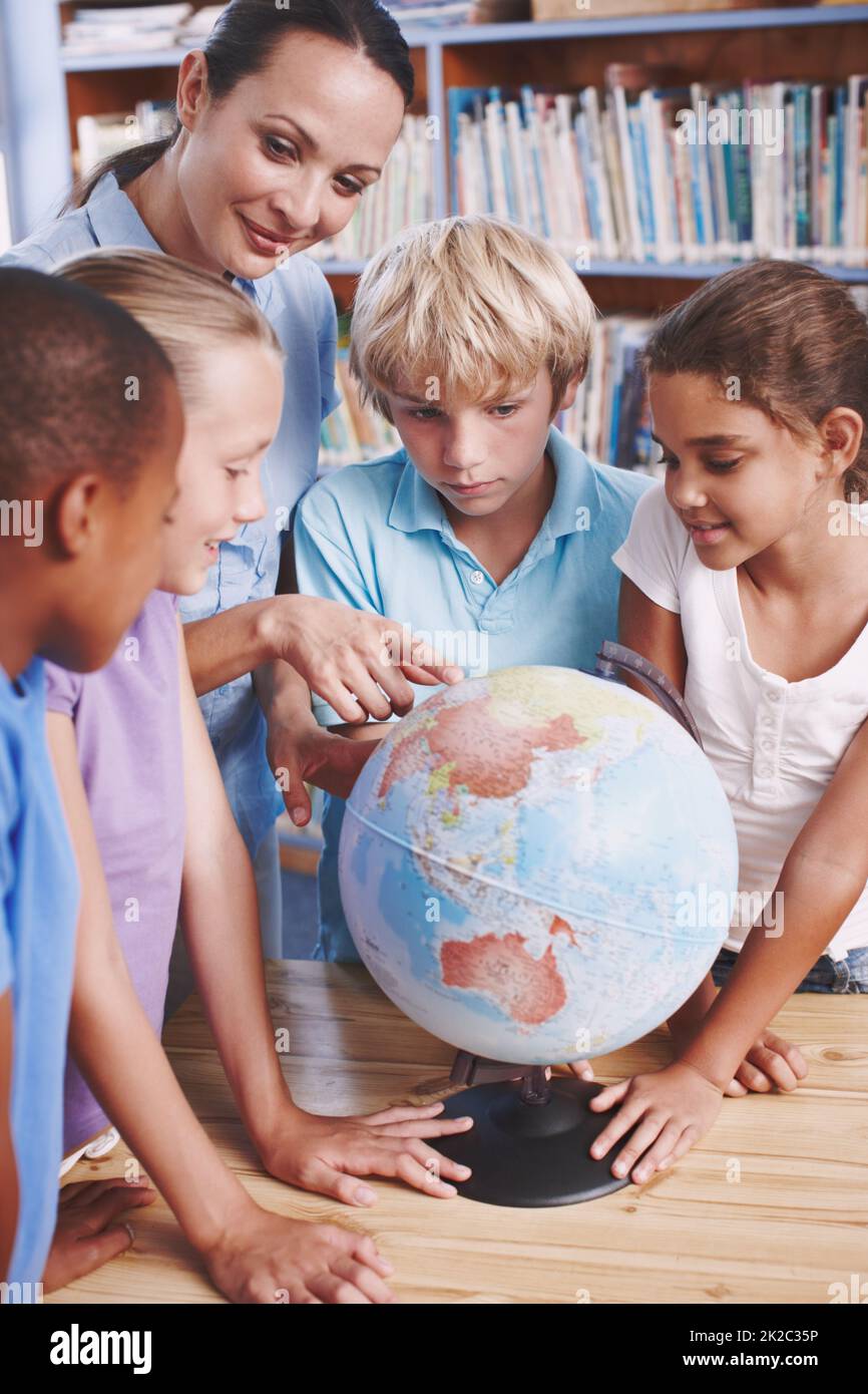 Pouvez-vous me dire où c'est. Un groupe d'écoliers apprenant le monde avec leur professeur de géographie. Banque D'Images