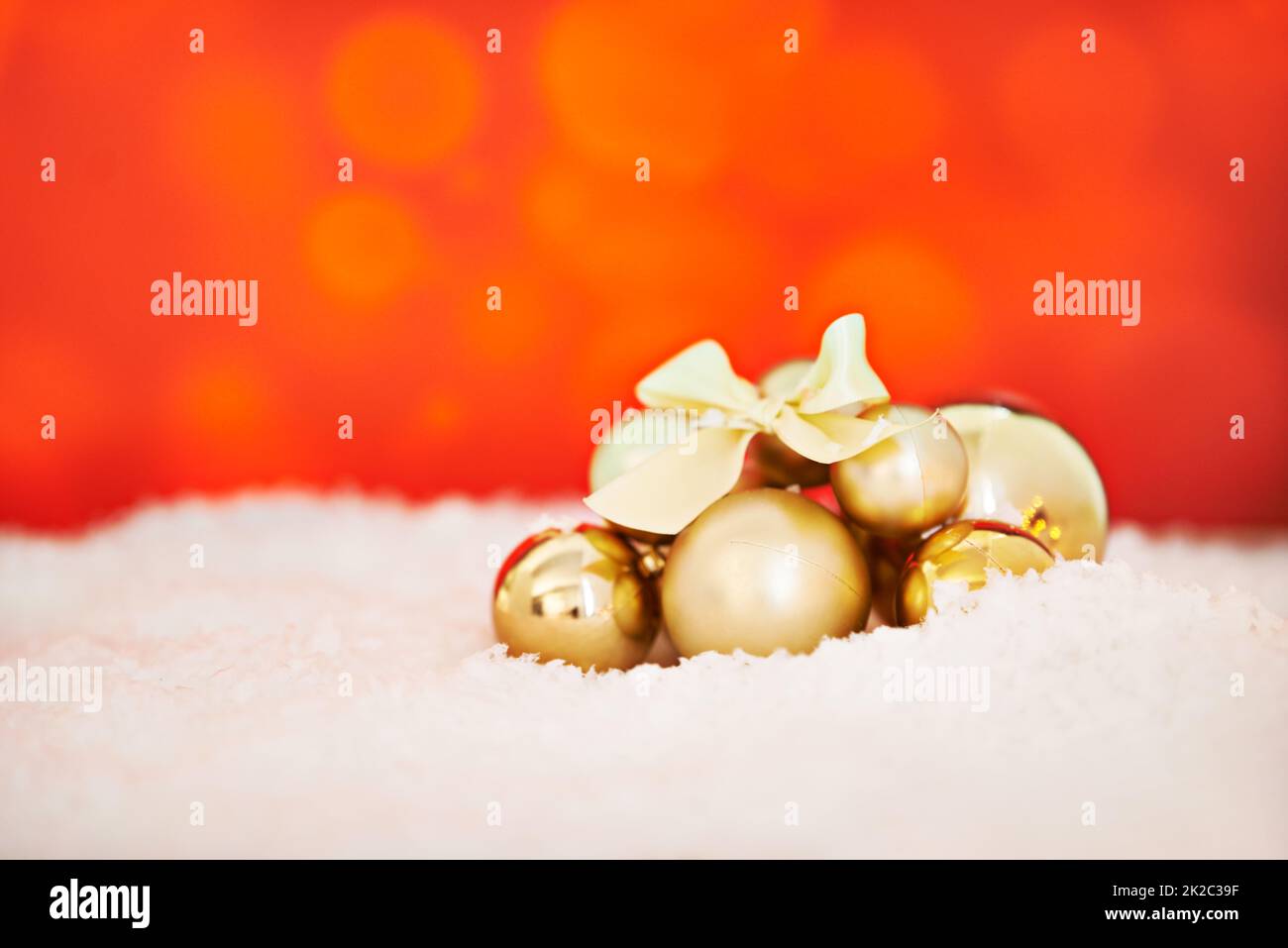 Fêtons vos fêtes. Studio photo d'un arrangement de décorations de Noël dorées sur fond rouge. Banque D'Images