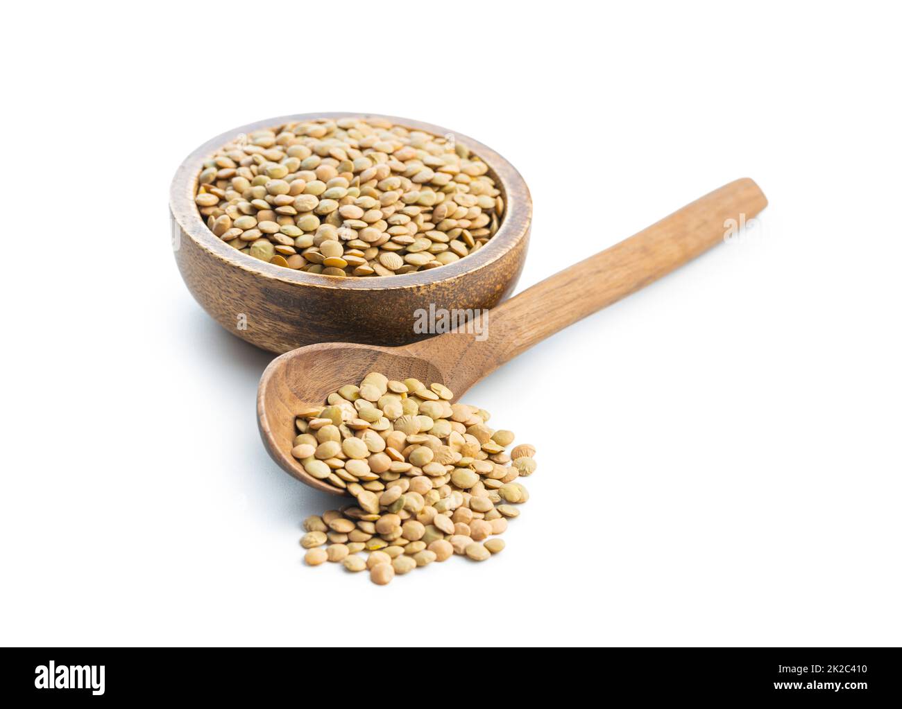 Lentilles brunes non cuites. Légume cru dans une cuillère en bois isolée sur fond blanc. Banque D'Images