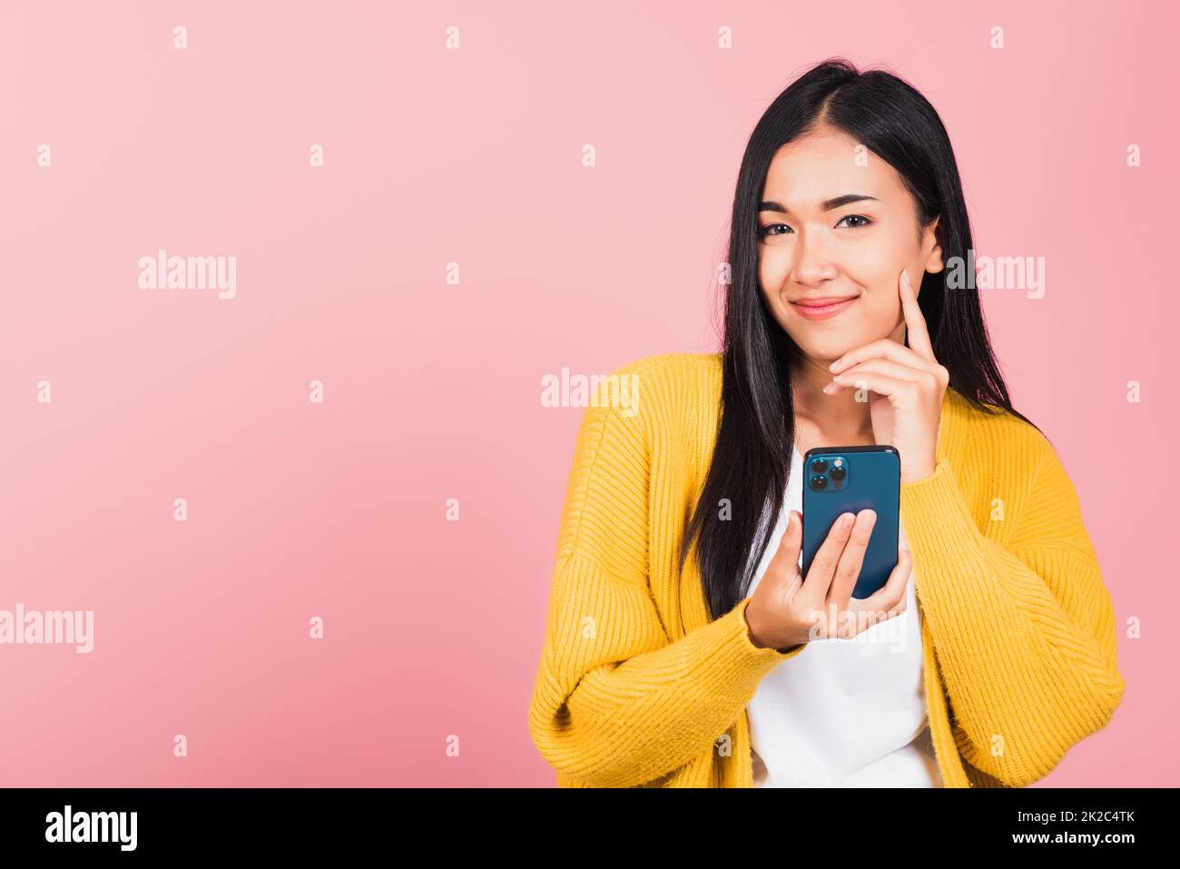 femme enthousiaste souriante tenant le téléphone mobile et pense l'idée Banque D'Images