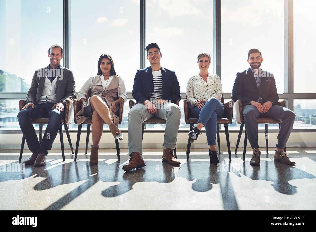Asseyez-vous et regardez-nous faire réussir. Portrait d'un groupe d'hommes d'affaires assis en ligne dans un bureau. Banque D'Images