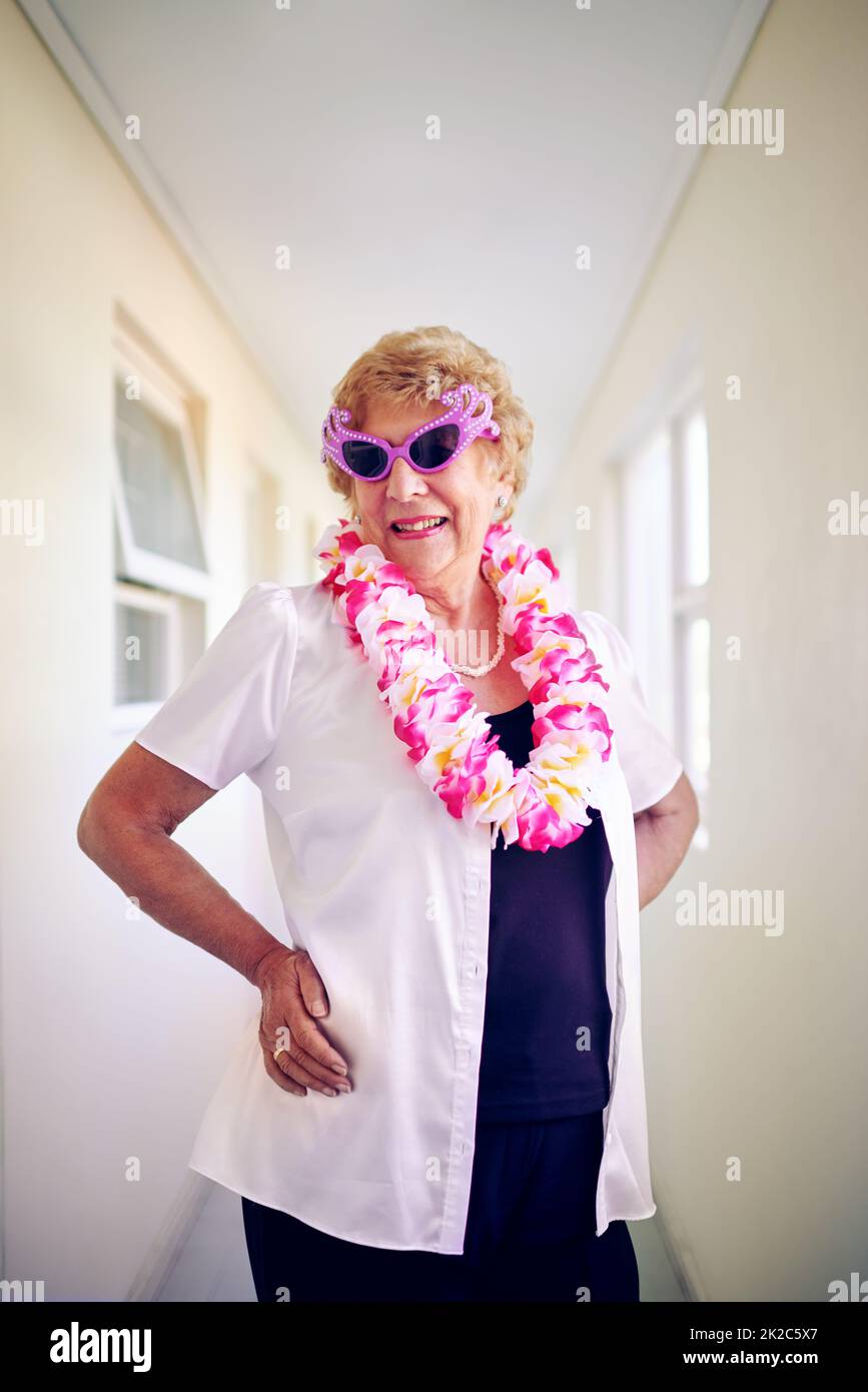 Je me sens encore jeune. Photo d'une femme âgée insouciante portant des lunettes roses et posant à l'intérieur d'un bâtiment. Banque D'Images