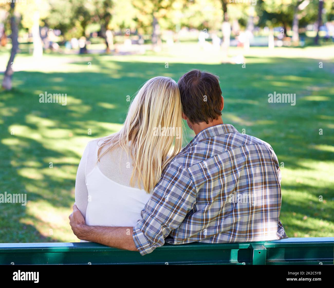 Garder le jeune amour vivant. Vue arrière d'un jeune couple affectueux assis sur un banc de parc. Banque D'Images