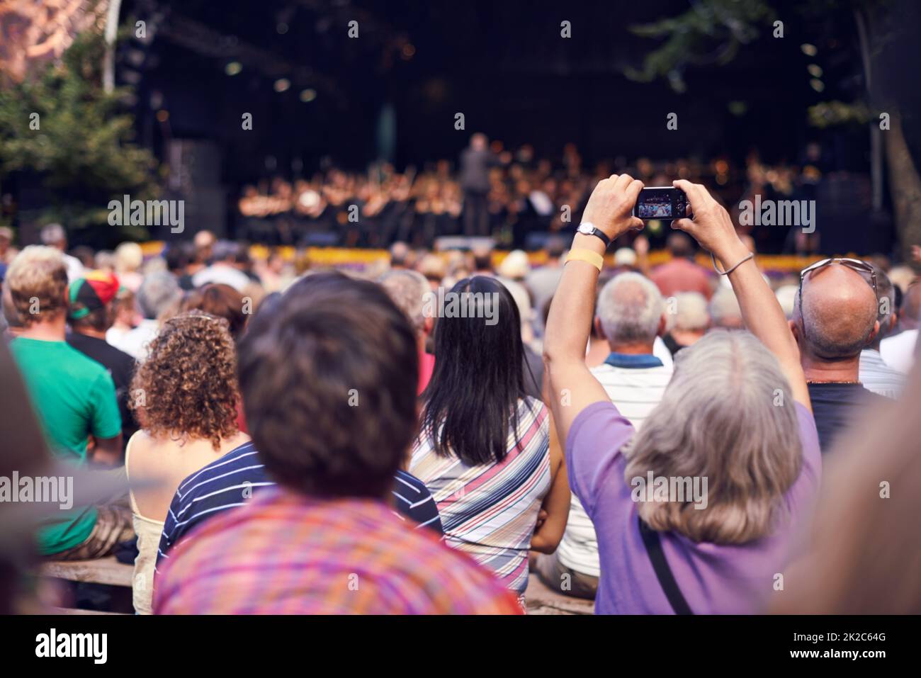 Les petits appareils photo capturent de superbes souvenirs. Photo d'une personne dans la foule tenant un appareil photo pour photographier un concert classique. Banque D'Images