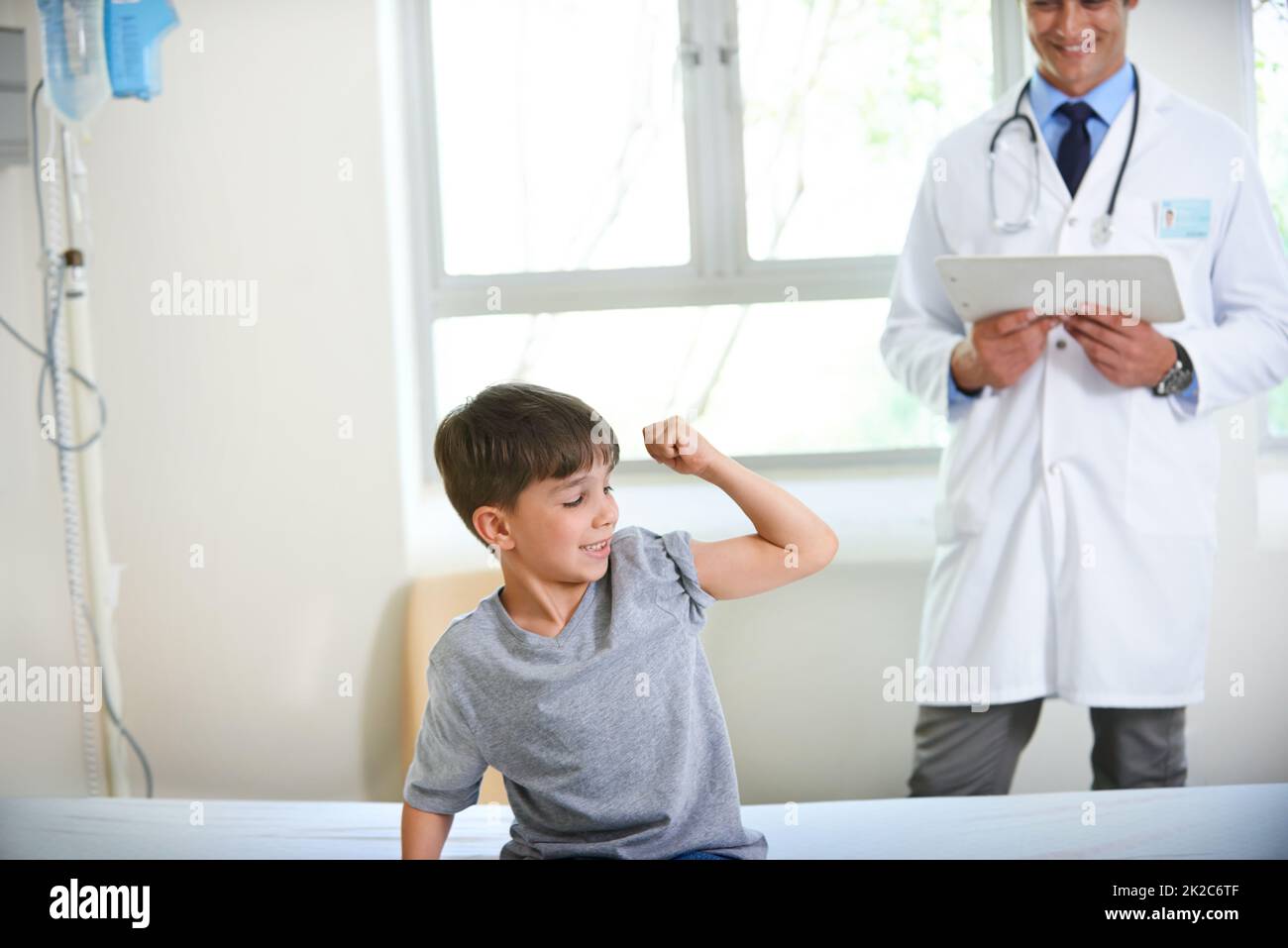 Regardez mes muscles se développer doc. Coup d'un jeune garçon montrant sa force et bravoure en fléchissant son bras. Banque D'Images