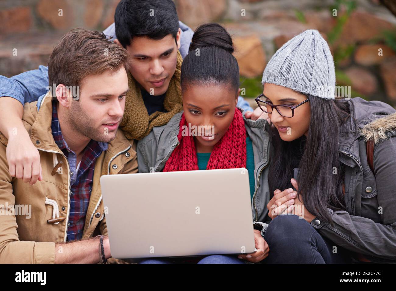 Amis et partenaires d'étude. Photo d'un groupe d'étudiants de l'université utilisant un ordinateur portable assis sur le campus. Banque D'Images