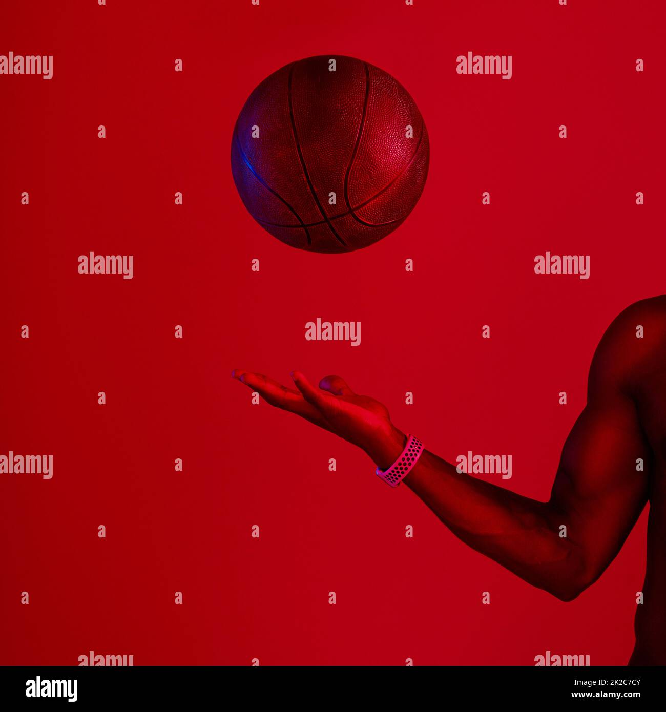 Ce que vous faites avec C'est comme tu veux.. Prise de vue filtrée rouge d'un sportif méconnaissable posant avec un ballon de basket dans le studio. Banque D'Images