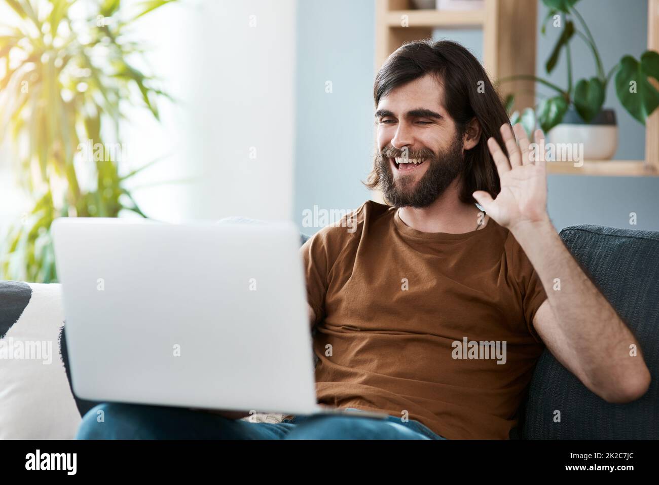 Bonjour de l'autre côté. Photo d'un beau jeune homme utilisant son ordinateur portable tout en se relaxant sur un canapé dans son salon. Banque D'Images