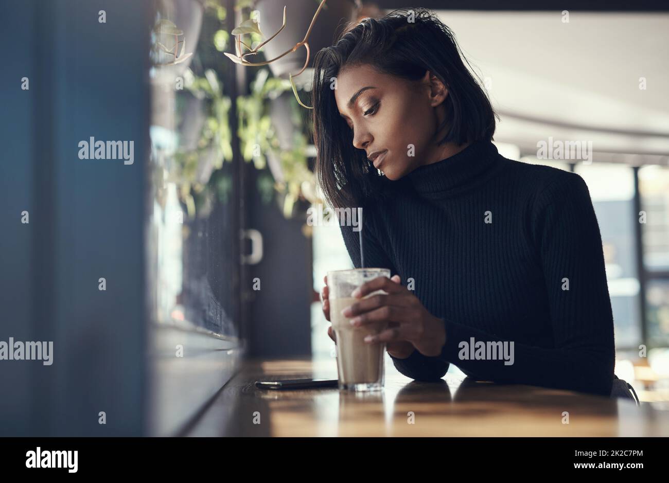 Ne laissez jamais une bonne femme attendre. Photo d'une belle jeune femme buvant un café glacé dans un café. Banque D'Images