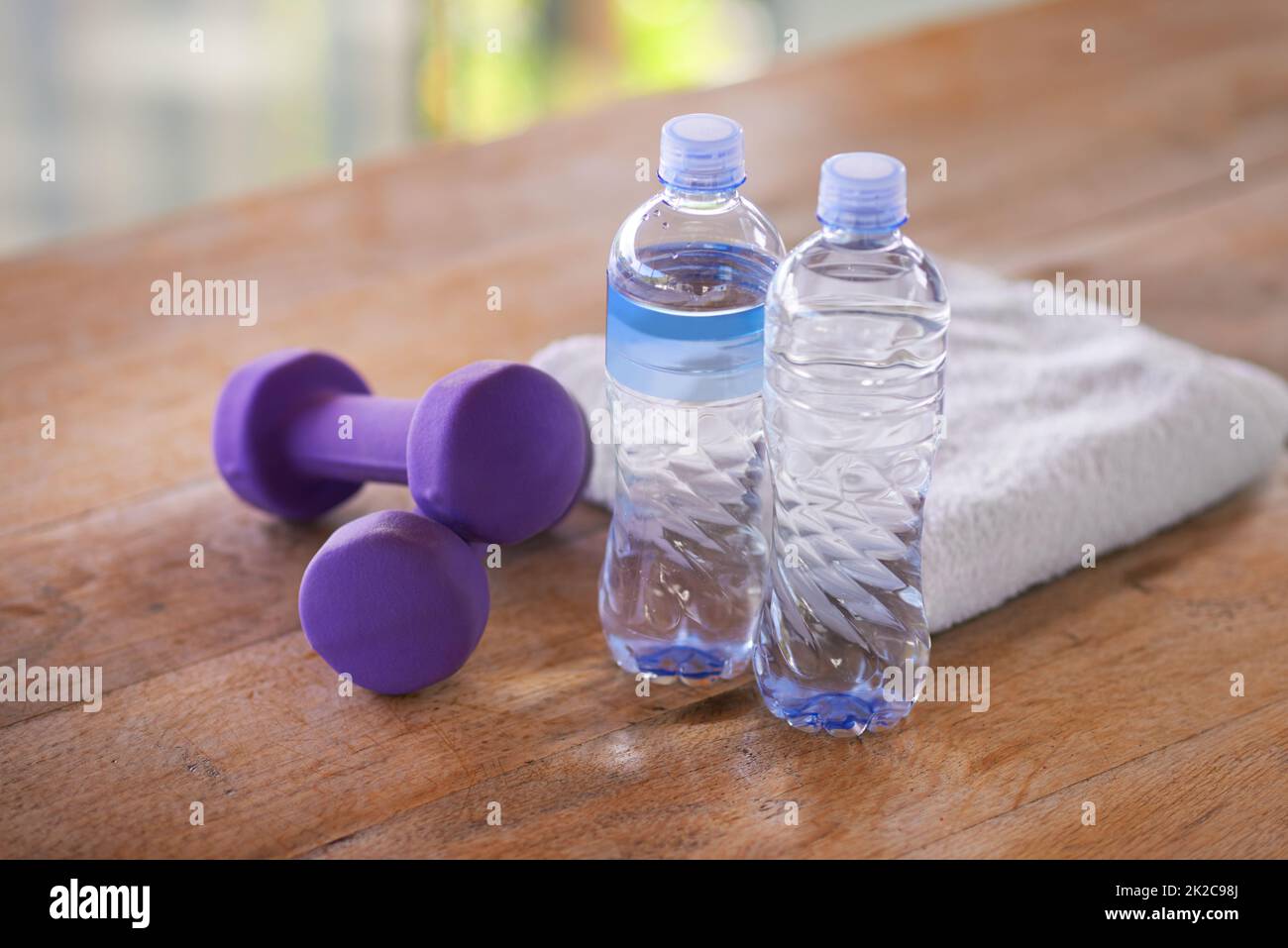 Tout ce dont j'ai besoin pour mon entraînement. Un coup de haltères, de bouteilles d'eau et d'une serviette sur une table en bois. Banque D'Images