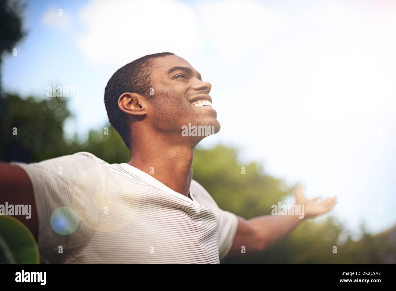 Lorsque la vie vous sourit, souriez en arrière. Photo d'un homme debout dehors avec ses bras étirés dans le plaisir. Banque D'Images