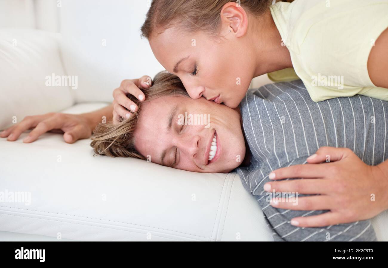 Quelle agréable façon de se réveiller. Prise de vue d'une femme qui se penche et embrasse son petit ami allongé sur un canapé. Banque D'Images