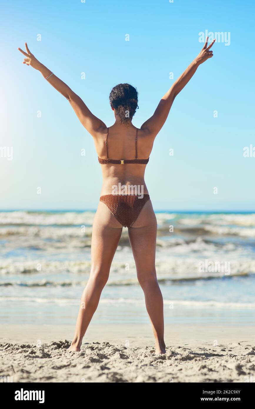 La plage est où je trouve ma paix. Vue arrière d'une jeune femme debout sur la plage. Banque D'Images