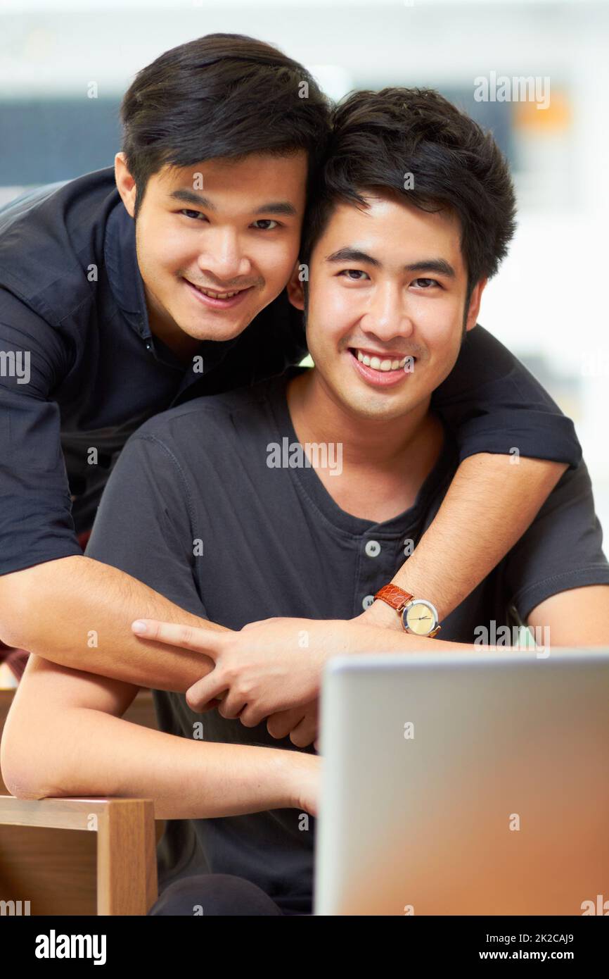 Le contenu juste pour être ensemble. Portrait d'un jeune couple gay affectueux se détendant à la maison avec un ordinateur portable. Banque D'Images