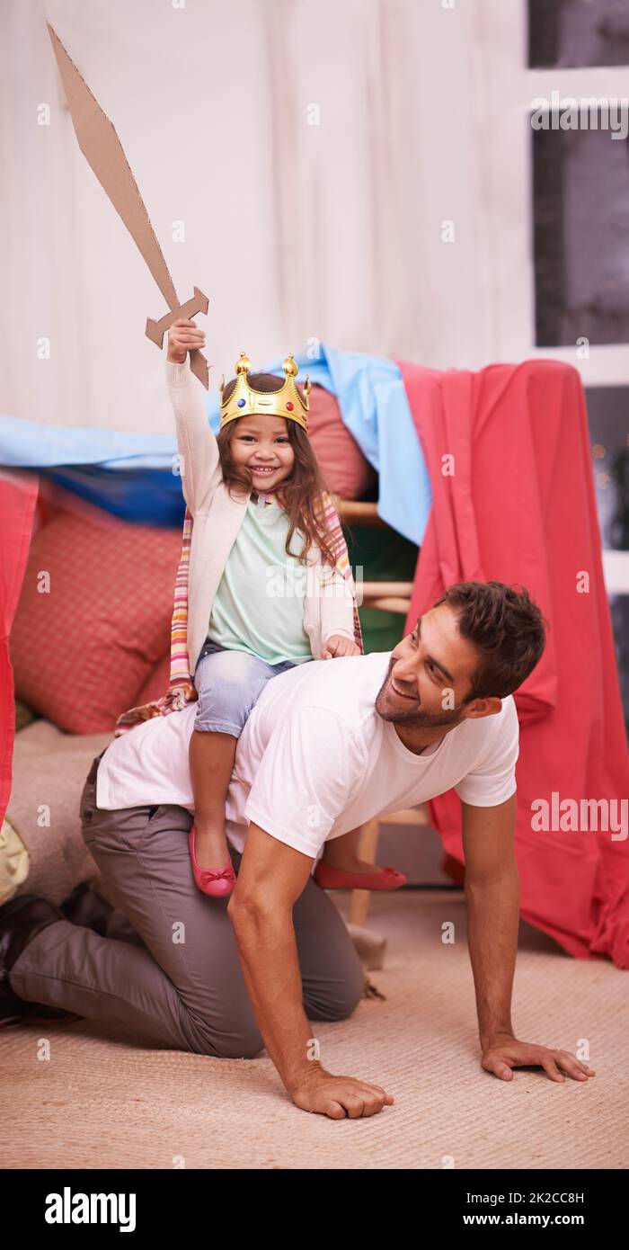 Beaucoup de plaisir. Une jolie petite fille habillée comme princesse tout en jouant à la maison avec son père. Banque D'Images