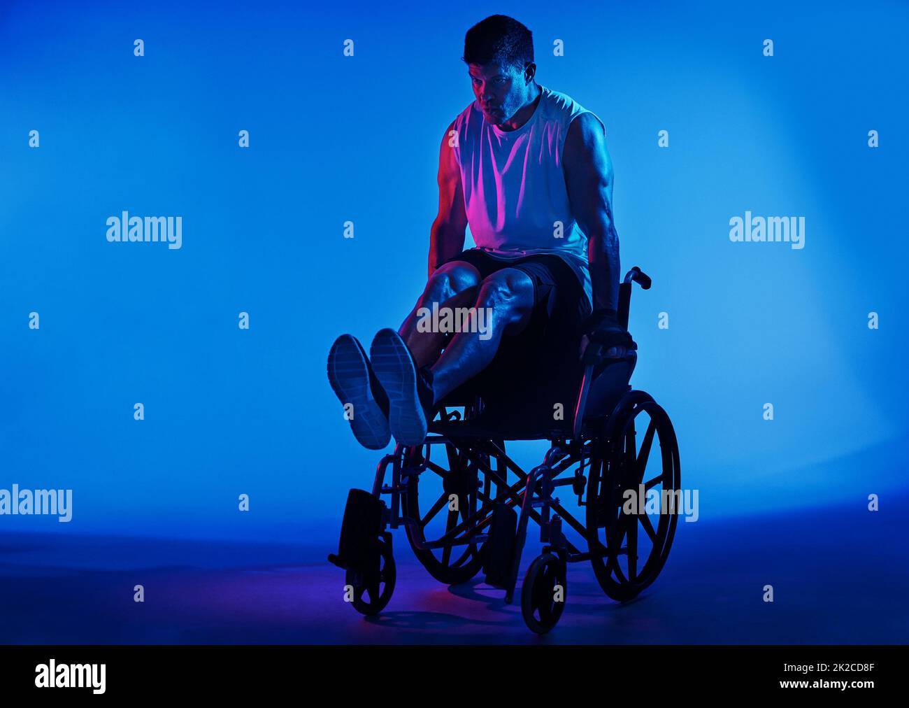 Le seul handicap est une mauvaise attitude. Vue filtrée bleue d'un homme qui s'exerce en étant assis dans son fauteuil roulant. Banque D'Images