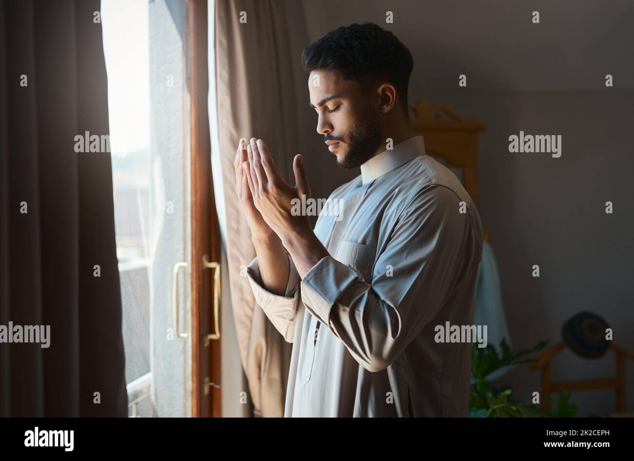 La prière est la reddition de toutes les peurs. Photo d'un jeune musulman qui priait dans le salon à la maison. Banque D'Images