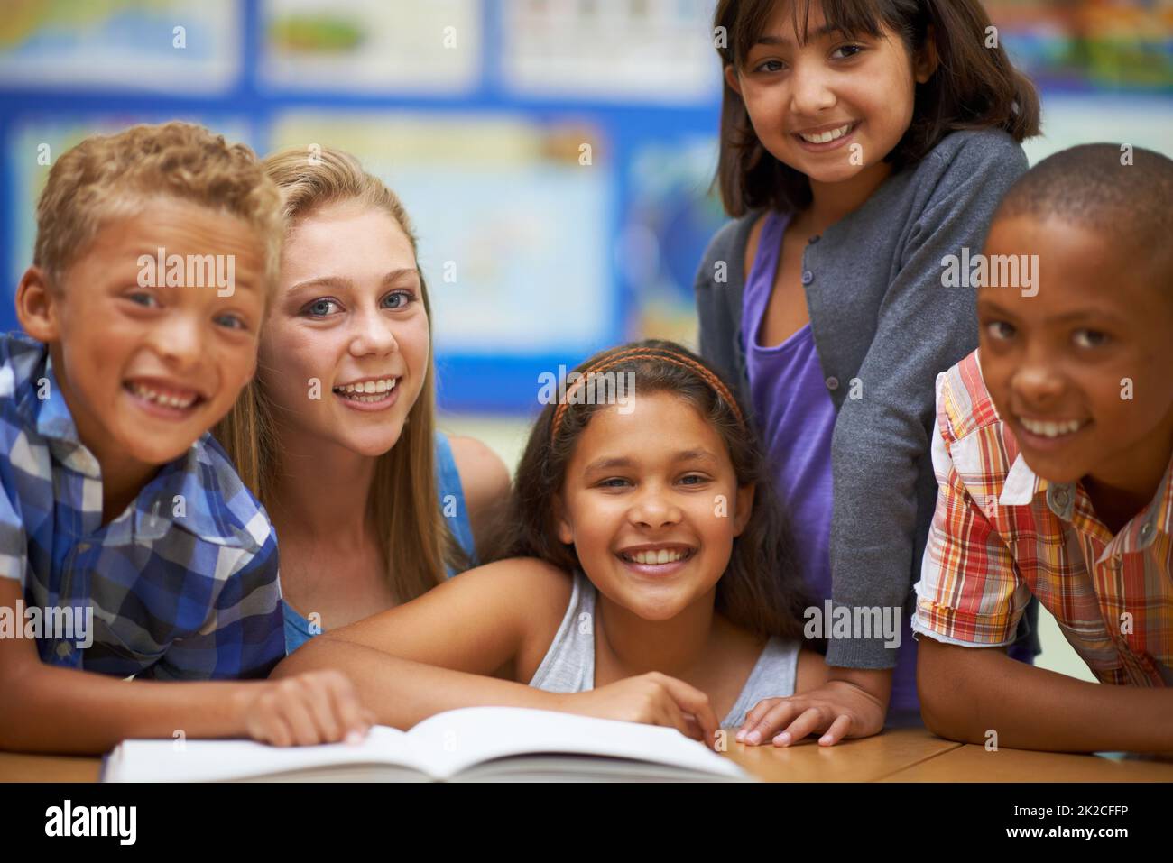 Apprendre au lire et l'aimer. Portrait d'un groupe d'élèves lisant un livre en classe. Banque D'Images