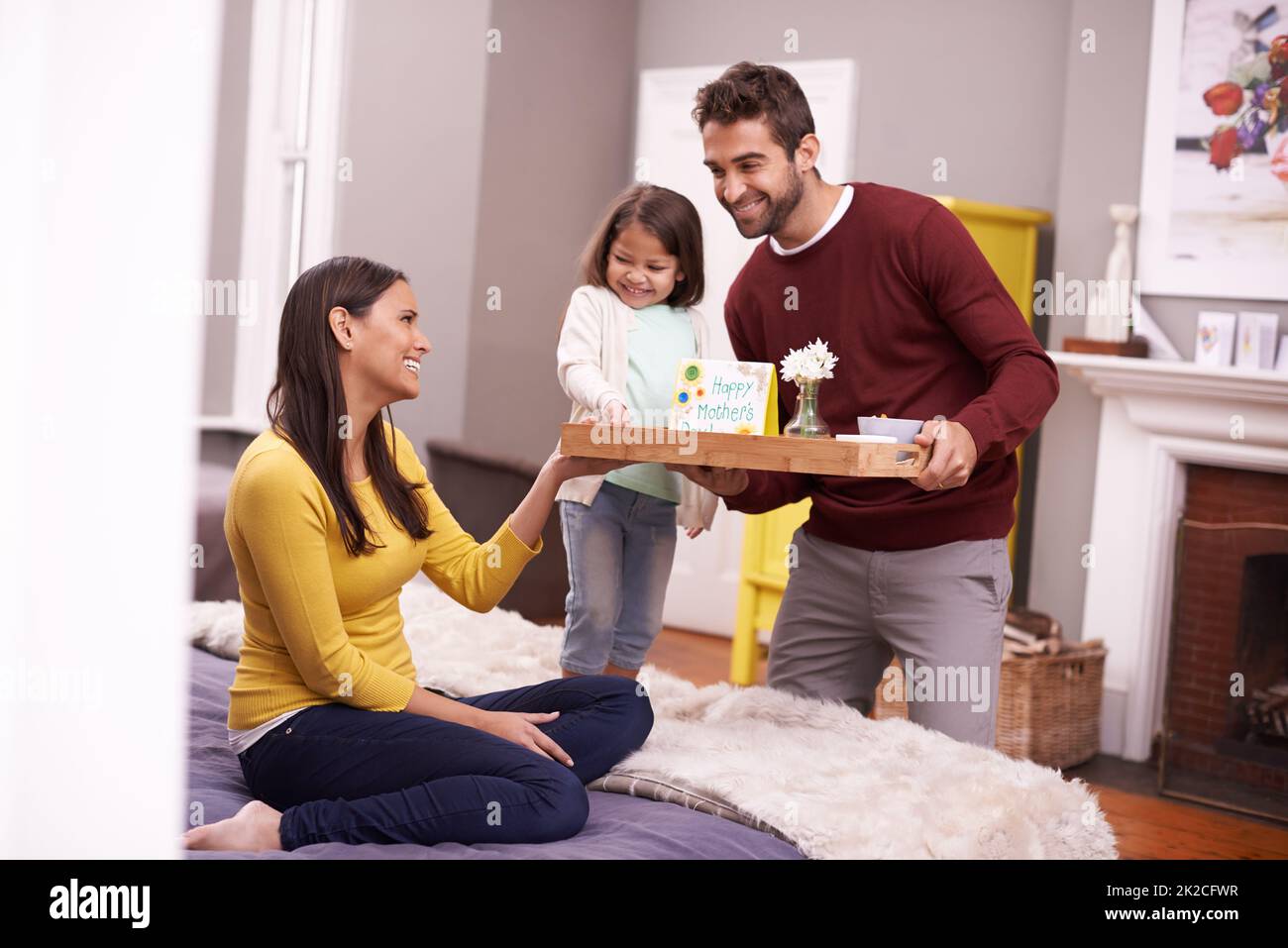 Maman qui se gâta. Un homme et sa fille apportent son petit déjeuner au lit de sa femme le jour de la fête des mères. Banque D'Images