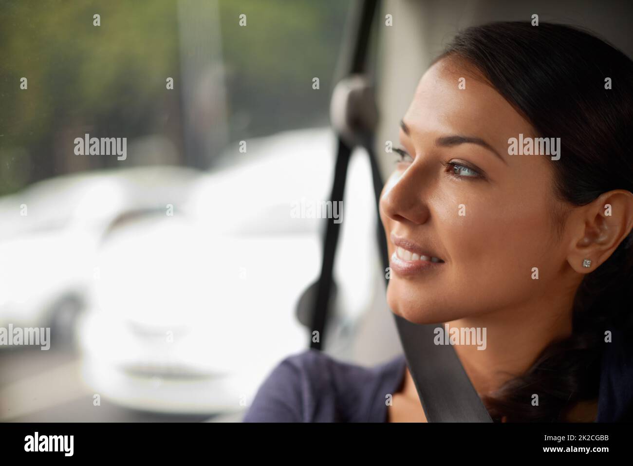 Une belle journée pour être sur la route. Une belle femme regardant par sa fenêtre tout en conduisant dans une voiture. Banque D'Images