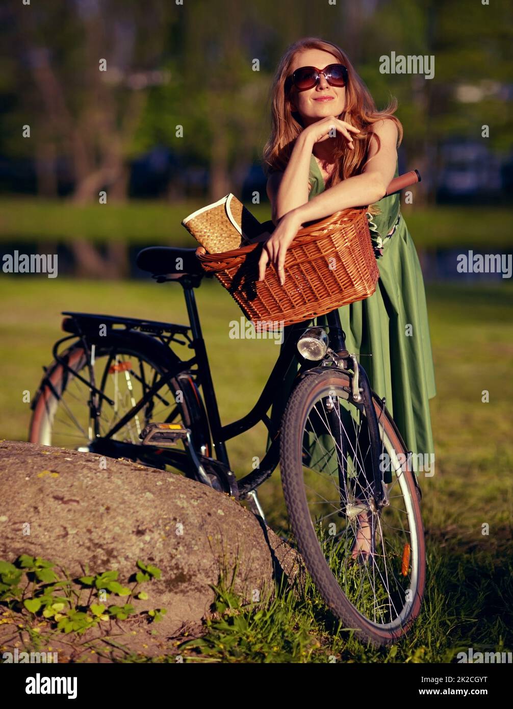 Prendre dans la tranquillité de la nature. Photo d'une belle jeune femme qui se détend dans le parc à côté de son vélo à l'ancienne. Banque D'Images