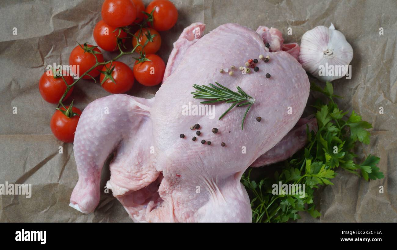 Poulet cru entier frais sur du papier de cuisson aux épices. Gros plan. Banque D'Images