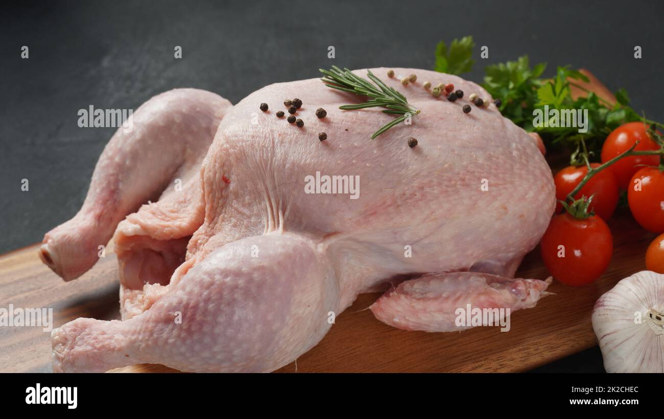 Poulet frais brut entier sur planche à découper en bois avec épices. Gros plan. Banque D'Images