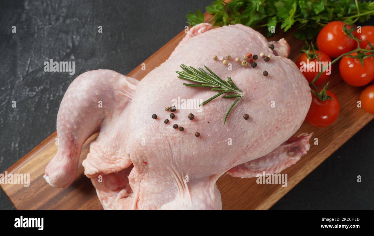 Poulet frais brut entier sur planche à découper en bois avec épices. Gros plan. Banque D'Images