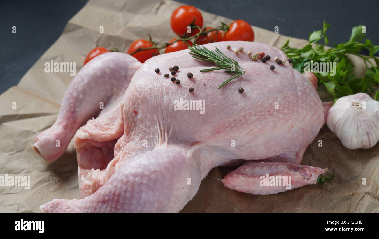 Poulet cru entier frais sur du papier de cuisson aux épices. Gros plan. Banque D'Images