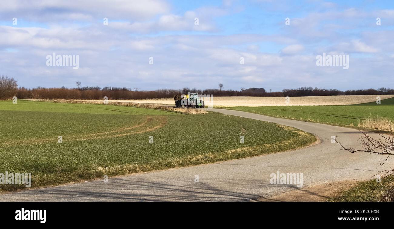 Un tracteur avec une grande remorque sur une route de campagne par beau temps. Banque D'Images