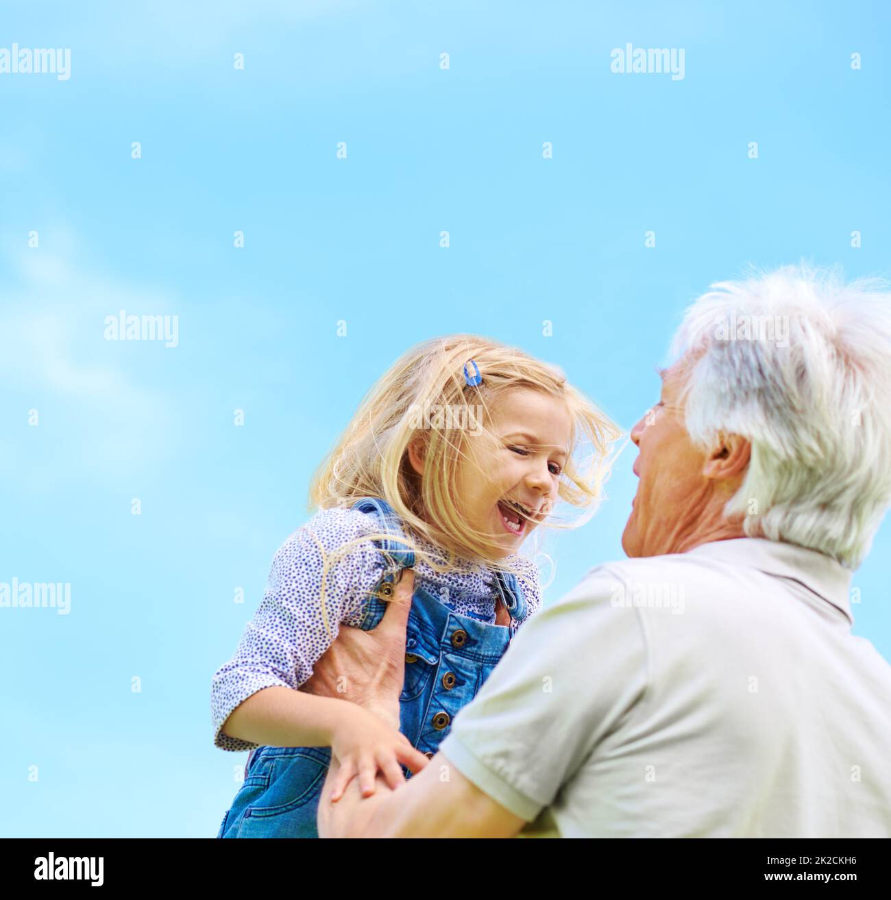Grand-père sait toujours comment faire rire elle. Photo d'un grand-père heureux soulevant sa petite-fille. Banque D'Images